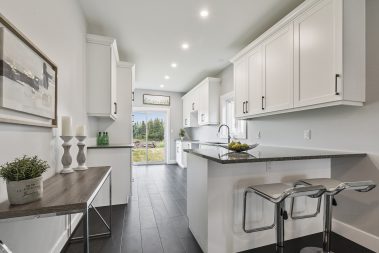simply white kitchen with black handles on cabinets and a breakfast bar with two seats
