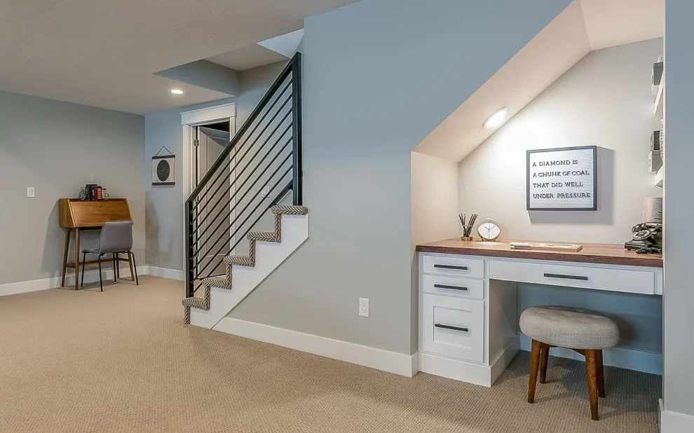 a home office with a desk and stairs in a newly renovated basement