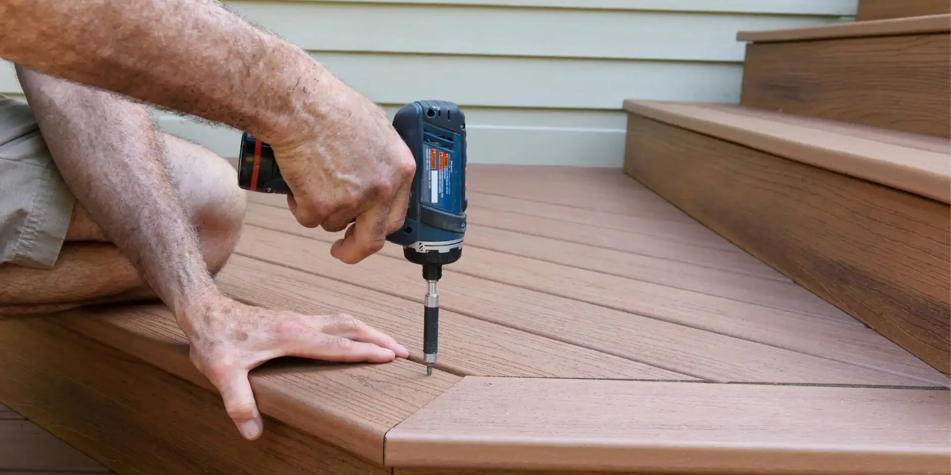 a person using a power drill to install a wooden deck
