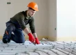 A contractor is installing heated floors inside a living room