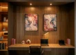 Modern home office with built in wooden shelving, warm lighting, minimalist desk setup, and abstract wall art.