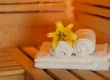 Rolled white towels with a yellow flower inside a warm wooden sauna inside the house.